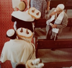 Grandpa kissing his tallit after touching the Torah.